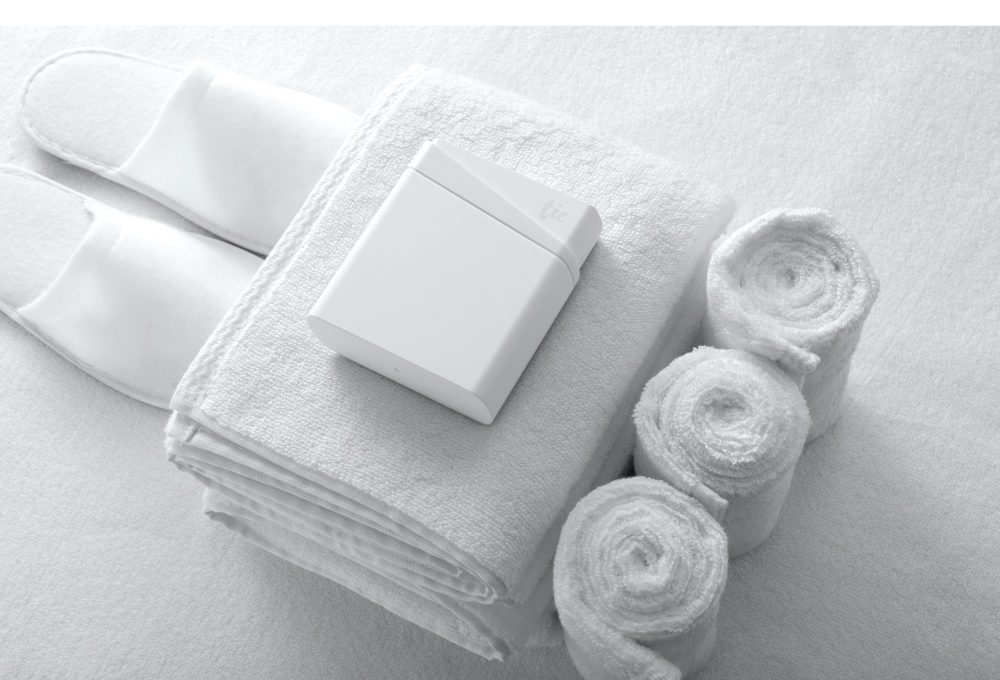 潔淨白色TIC ORAL CARE 旅行清潔用品組放在純白毛巾及室內拖鞋旁
